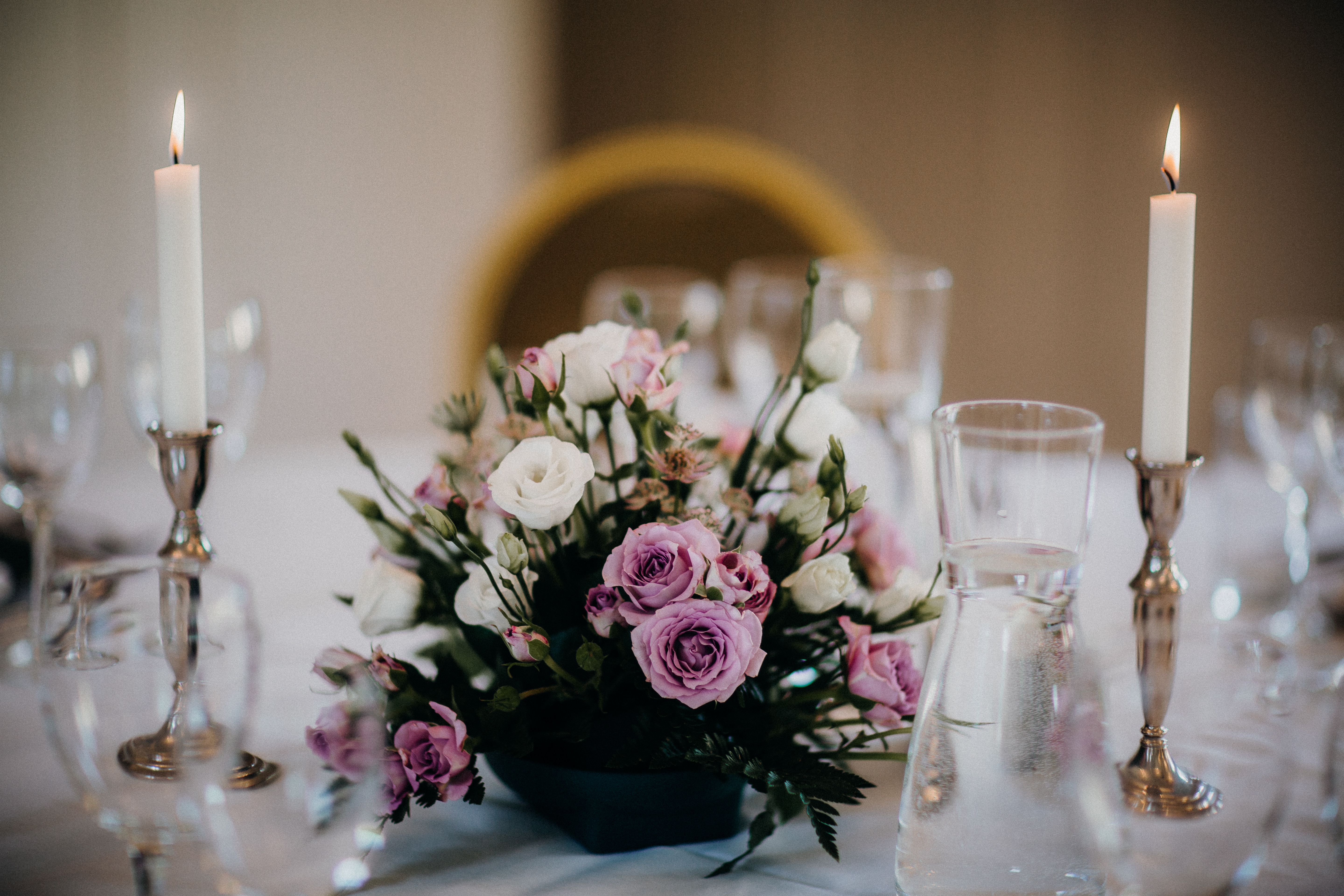 Lavender and white flowers between candles on an event table